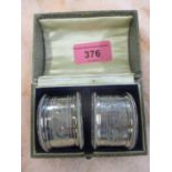 A pair of gadrooned and chased silver napkin rings in presentation case