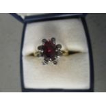 An 18ct yellow gold ruby and diamond cluster ring, claw set oval ruby surrounded by eight diamonds