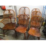 A set of four Windsor wheel-back elm seated dining chairs and two carvers, having pierced splats,