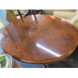 A walnut oval dining table on central pedestal base