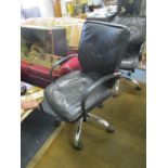 A faux black leather and chrome swivel office chair with arms and castors