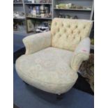 A Victorian button back deep armchair on two front turned legs