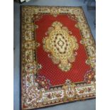 A Mumtaz red ground rug with black and gold border and central medallion
