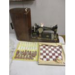 A Singer sewing machine in an oak case and an onyx chess board and matching pieces