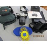 A Pentax MZ50 camera and travel case, modern Minox binoculars and a New Zealand sun dial