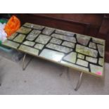 A mid century coffee table with a faux mother of pearl top on brass finished cross-over legs, 17"