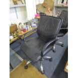 A faux black leather and chrome swivel office chair with arms and castors