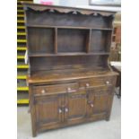 A 1930s oak dresser with a plate rack over two drawers and three linenfold panelled doors, 71 3/4"