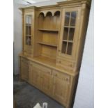 A large modern pine dresser having twin glazed doors flanking two open shelves above drawers and