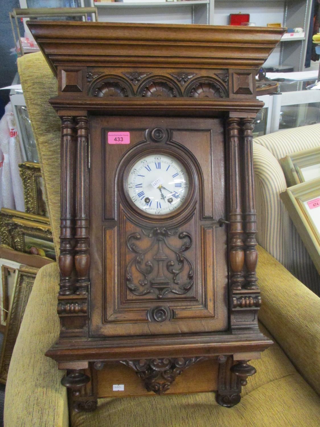 A late 19th century walnut carved wall hanging clock, fitted with an eight day movement