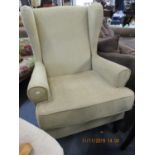 A modern wing-back armchair with chenille upholstery on dark stained legs