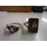 A gold coloured ring set with an amethyst and sapphires and a gold coloured ring set with a citrine