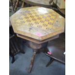 A Victorian walnut sewing/games table having an octagonal hinged top and a tripod base