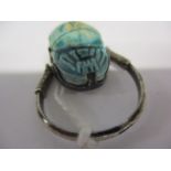 A white metal Egyptian ring set with a hinged blue glazed scarab beetle with marks to the ring