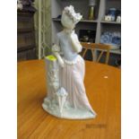 A Lladro figure of a lady leaning against a pillar with her umbrella