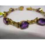 A yellow gold and amethyst bracelet set with eight stones and rope twist style links stamped 750