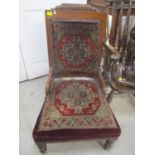 A Victorian walnut nursing chair on two turned front legs and castors