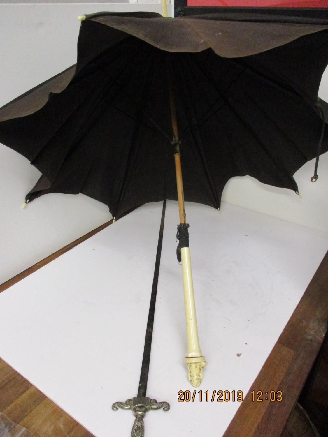 An early 20th century ivory handled parasol with a carved figure and a silver plated ceremonial