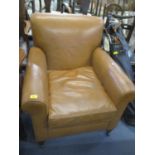 A mid tan leather upholstered armchair on tapered front legs and castors