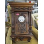 A late 19th century walnut carved wall hanging clock, fitted with an eight day movement