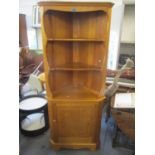 An Ercol pine corner cabinet having open shelves above a single cupboard door, 72"h x 30"w