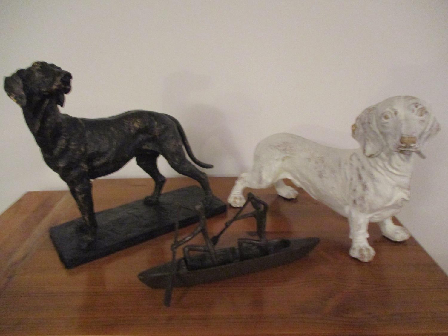 Two models of dogs and a bronze model of a canoe with two figures rowing