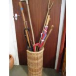 A selection of miscellaneous walking canes and mixed sticks and a wicker basket