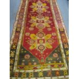 A 1940s Persian rug having a red, yellow, pink and dark green ground, 100" x 49", approximately