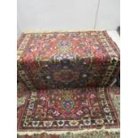 An Iranian hand woven rug decorated with floral and geometric designs on a blue and red ground,