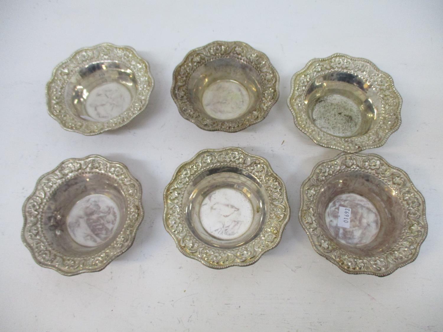 A set of six silver coloured metal dishes, each with a floral and leaf embossed and chased, shaped