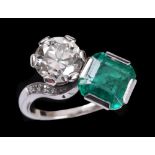 An Emerald and Diamond two stone crossover Ring claw-set step-cut emerald and old-cut diamond,