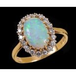 An Opal and Diamond Cluster Ring claw-set oval opal cabochon within frame of brilliant-cut