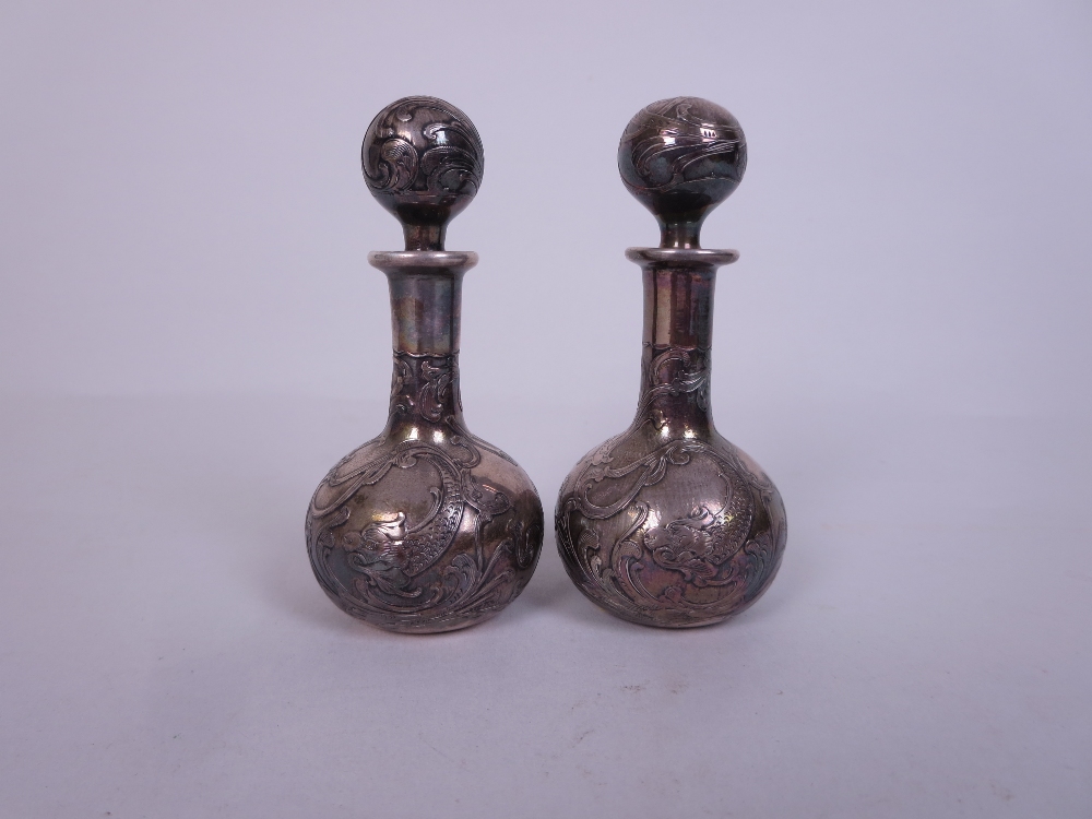 A pair of Art Nouveau small silver overlaid Scent Bottles and Stoppers of club shape with dolphin