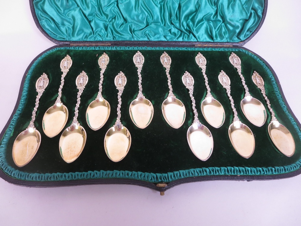 One dozen Victorian silver-gilt Dessert Spoons with scroll stems and figure finials, London 1893, in