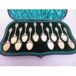 One dozen Victorian silver-gilt Dessert Spoons with scroll stems and figure finials, London 1893, in