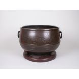 A bronzed two handled Cauldron with leaf design on later base, 13in diam