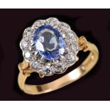 A Sapphire and Diamond Cluster Ring claw-set oval-cut sapphire with frame of twelve pavé-set