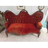 A Victorian walnut framed triple humpback Sofa with carved floral decoration and red plush