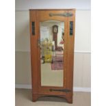 An Arts & Crafts oak Wardrobe with single mirror door flanked by rectangular green glass and