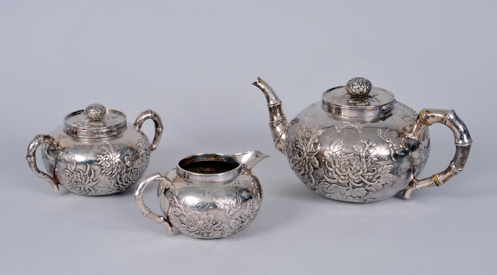 A Chinese silver three piece Tea Service decorated insects and chrysanthemum, the teapot and sucrier