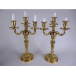 A pair of gilt metal three branch, four light Candelabra with beaded rims, lion mask and swag