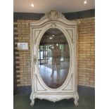 A 19th Century French cream and gilt painted Cabinet with oval glazed door, carved shell