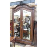 A 19th Century walnut Armoire fitted pair of mirror doors beneath leafage carved surmount upon