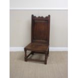 A late 17th Century oak Nursing Chair with shaped top rail, fielded panel back, solid seat on