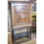 An antique oak Cupboard with dentil cornice above a single fielded panelled door, enclosing