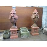 A pair of terracotta lidded Urns on square plinths with trailing ribbon and fruit swag relief