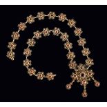 An early 20th Century gilt metal Garnet Necklace constructed from filigree rosettes each set rose-
