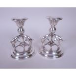 A pair of modern designer silver Candlesticks with three dolphin supports on circular bases,