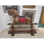 A 19th Century skin covered Rocking Horse with leather saddle and tack mounted on pine base