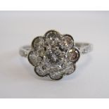 A Diamond Cluster Ring claw-set brilliant-cut stone within frame of eight pavé-set smaller stones in